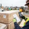 Encargado digitalizando albaranes de obra con el móvil junto al material recibido
